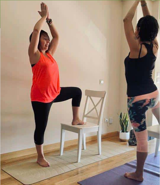 Paula Estrada, profesora de Yoga Oncológico, realizando una variante de las postura del árbol con una silla