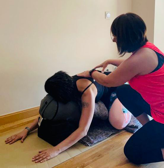 Paula Estrada, profesora de Yoga Oncológico, ajustando una postura de relajación durante una clase de yoga para personas con cáncer
